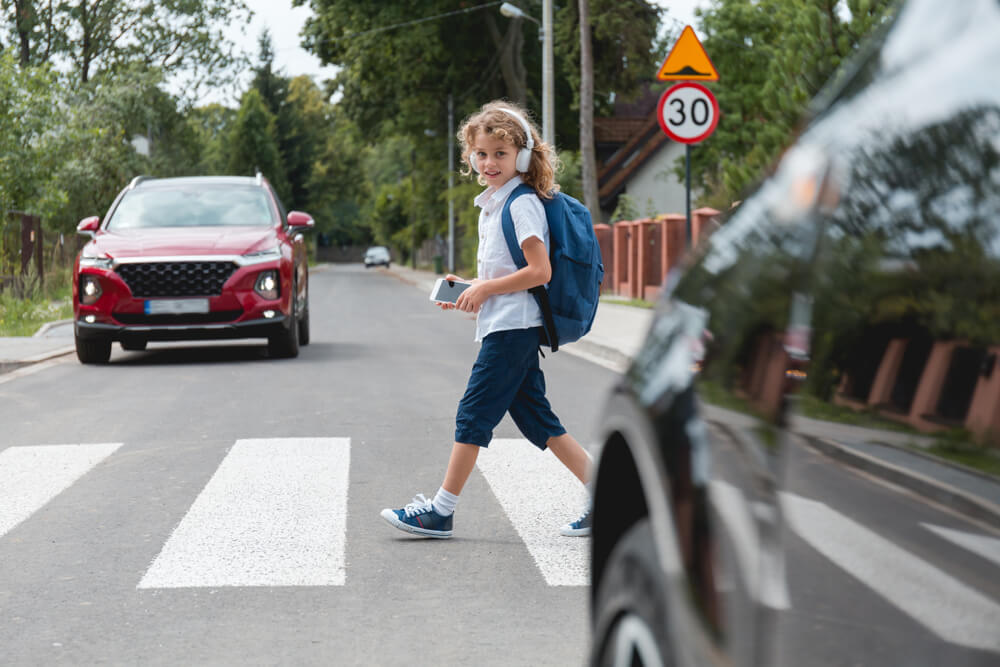 Kid crossing the road in the pedestrian lane.