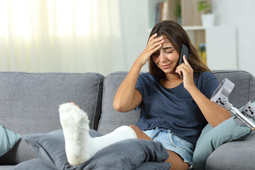 Injured lady with crutches crying while answering the phone.